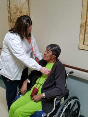 Nurse checking a resident's heartbeat in a hallway