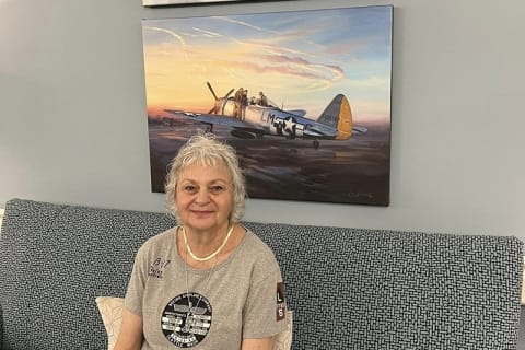 Resident posing in a facility interior with airplane artwork