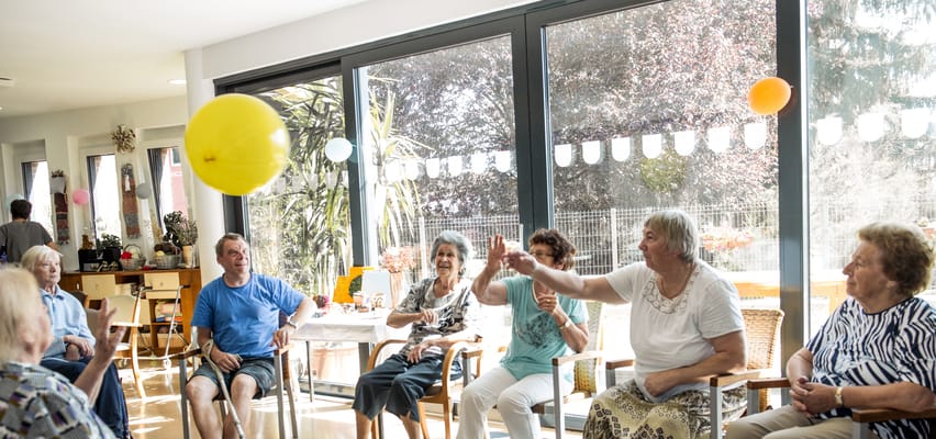 Residents playing with a balloon in a cheerful indoor space