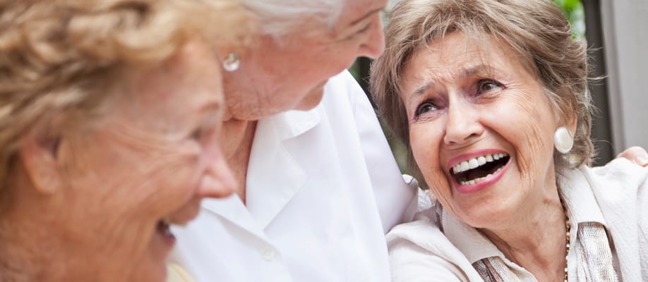 Three elderly women sharing a joyful moment together