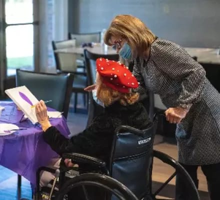 Staff assisting a resident in an activity room