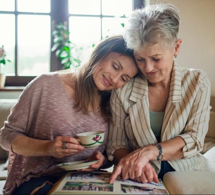 Two women sharing memories while looking at a photo album