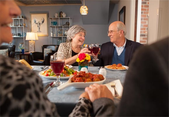 Residents enjoying a meal and toast in the dining room