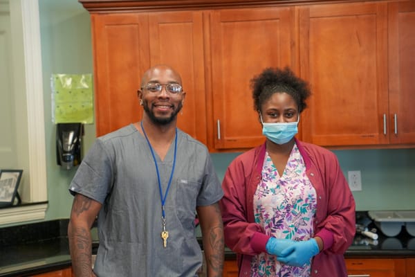 Two staff members smiling in a facility kitchen