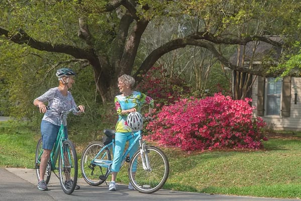 Two seniors enjoying a bike ride in a garden