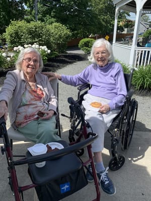 Two residents enjoying snacks outside on a sunny day