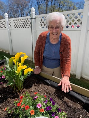 Resident gardening with colorful flowers in sunlit outdoor space
