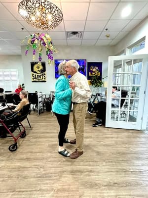 Couple dancing in a common area with residents present