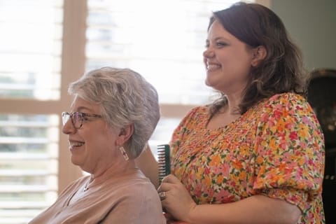 Resident receiving a hair styling in a common area