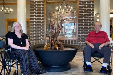 Residents enjoying time in a common area with a water fountain