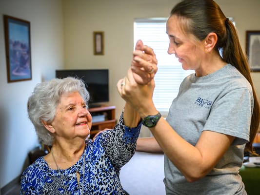 Caregiver assisting a resident with mobility in a warm interior setting