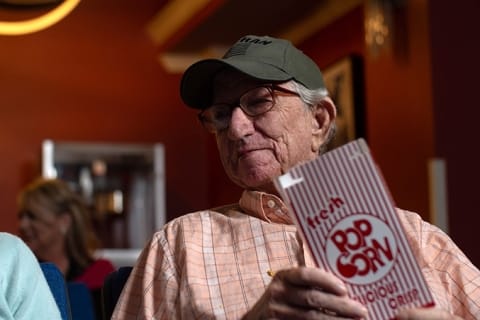 Elderly man enjoying popcorn in a social setting