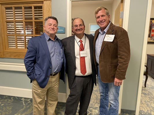 Three men smiling together at an event