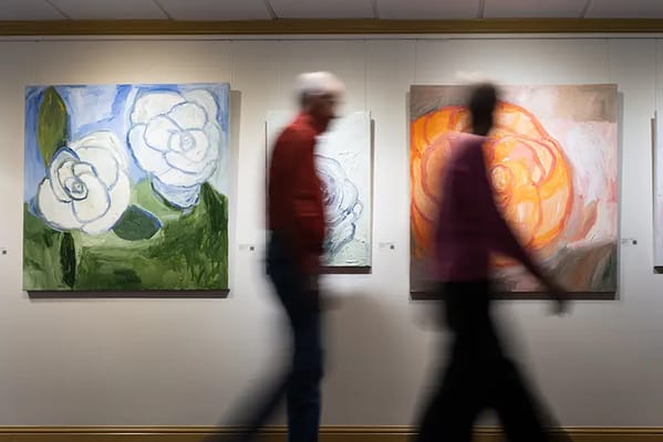 Residents walking past flower paintings in an activity area