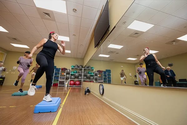 Residents participating in a fitness class in a bright activity room