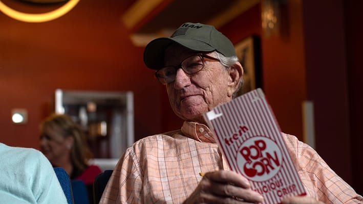 Resident enjoying popcorn during a movie activity