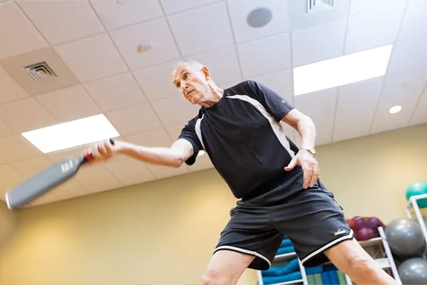 Senior man playing pickleball indoors