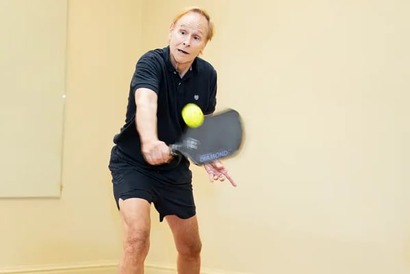 Resident playing pickleball in an activity room