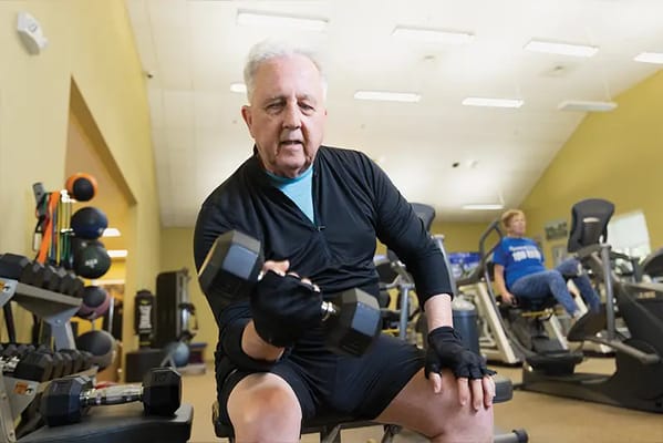 Resident exercising with dumbbells in fitness area
