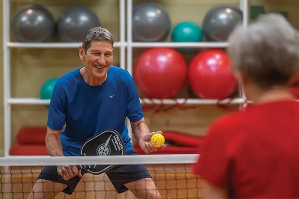 Residents playing pickleball in an activity room