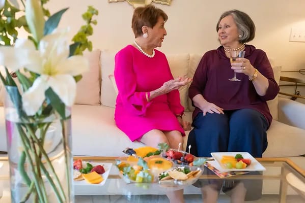 Two women enjoying snacks and drinks in a cozy setting.