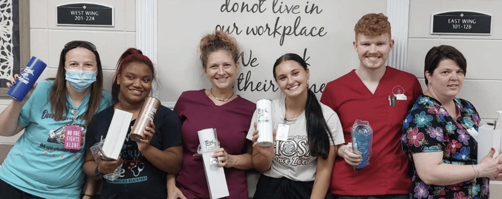 Staff posing with cups in a common area