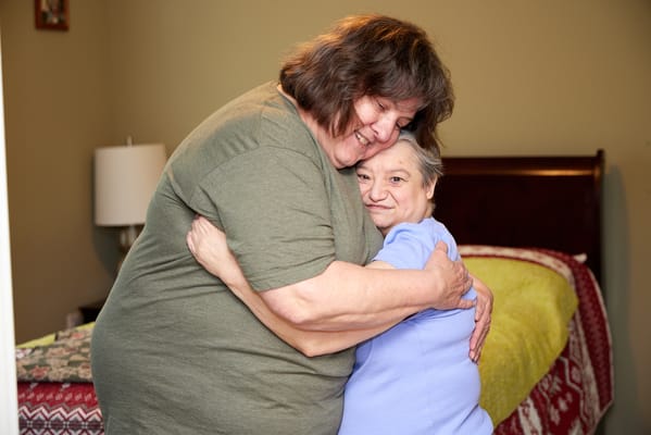 Caregiver and resident sharing a warm embrace in a room