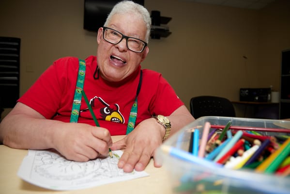Resident coloring in an activity room with vibrant crayons