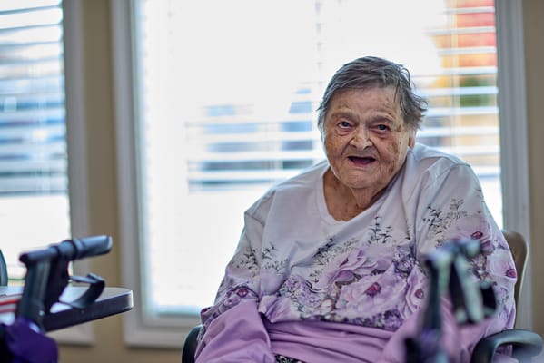 An elderly woman smiling while seated indoors