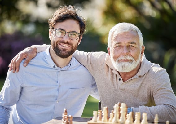 Resident enjoying chess game with visitor outdoors