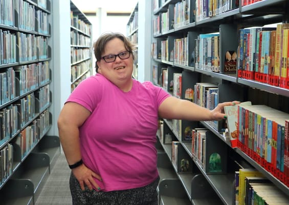 A resident smiling while browsing books in the library