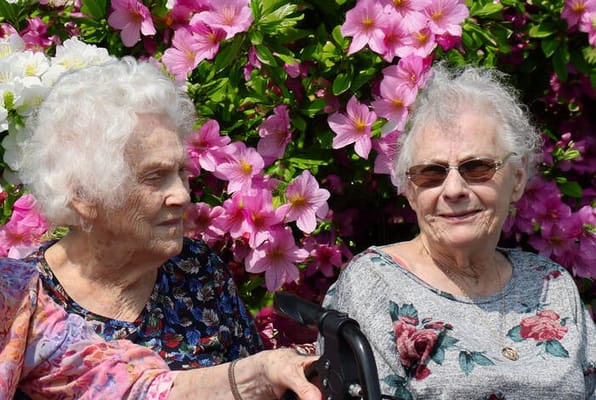 Two residents sitting in front of blooming flowers