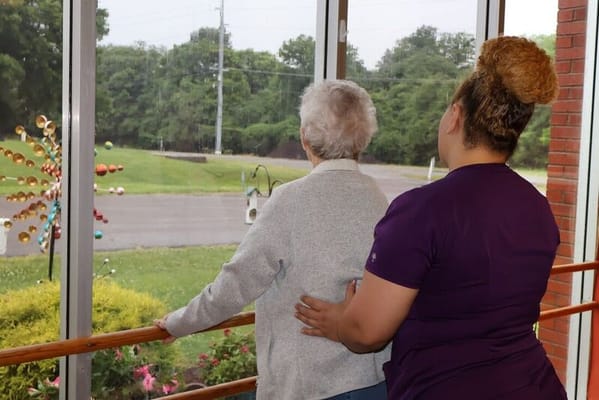 Staff assisting a resident by a window