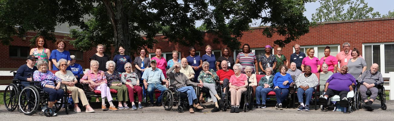 Residents and staff posing outside in a group photo