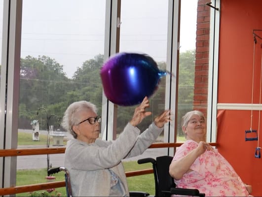 Residents playing with a balloon in an activity room
