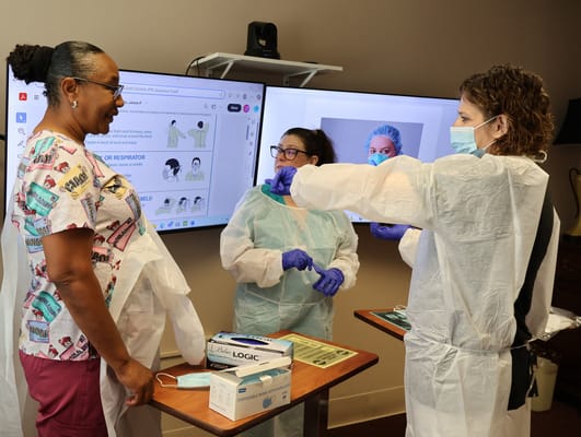 Staff demonstrating personal protective equipment to a resident