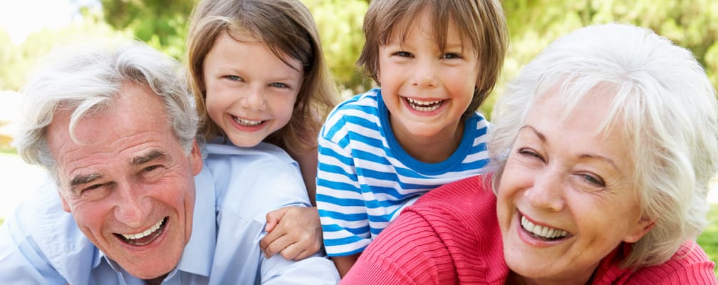 Smiling elderly couple with children outdoors