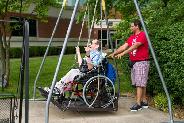 Resident swinging with staff assistance in an outdoor area