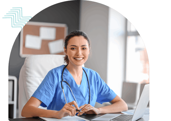 A smiling nurse in a blue uniform at a desk