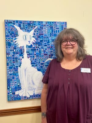 Staff member posing with artwork in a common area