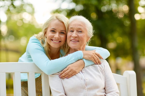 A cheerful woman and senior woman sitting together outdoors