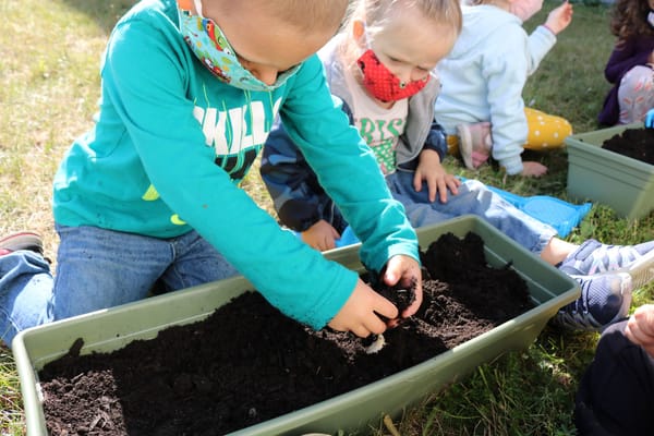 Children planting seeds in outdoor garden boxes