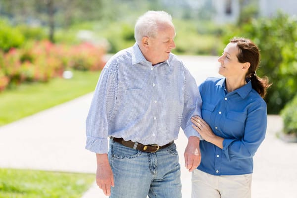 A resident walking with staff in a lush garden path