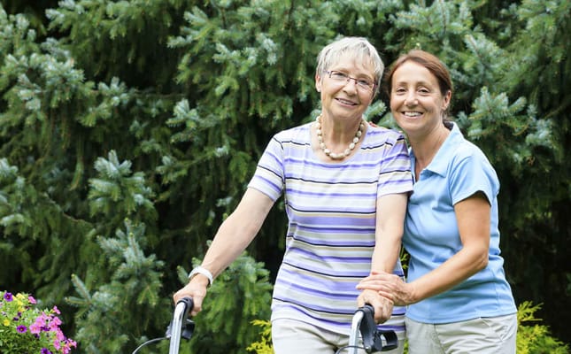 Senior resident and staff member smiling in a garden