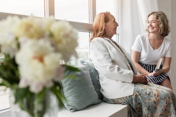 Resident and staff engaging in conversation by a window