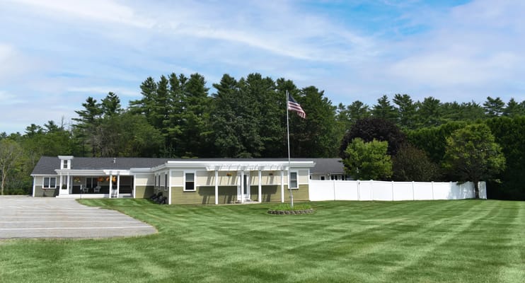 Exterior view of Bella Point Bridgton with flag and lawn