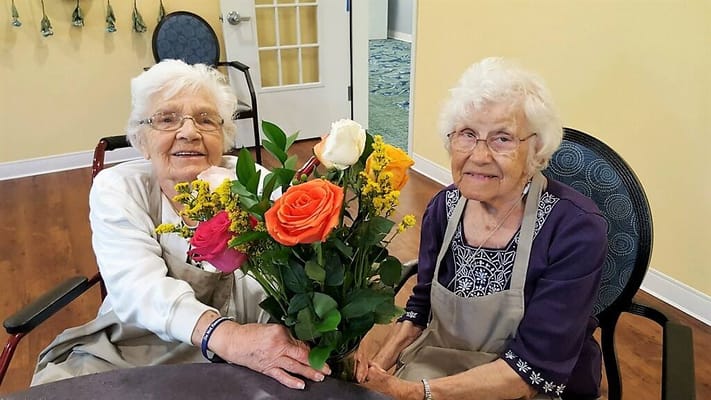 Two residents with a flower bouquet in a common area