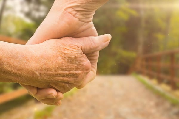 Two hands holding each other outdoors