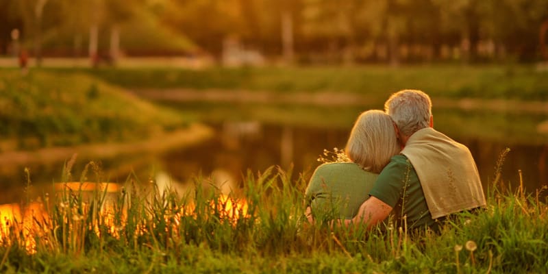 Couple sitting by a serene pond at sunset