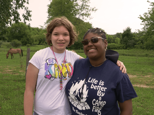 Two smiling women in a grassy outdoor area